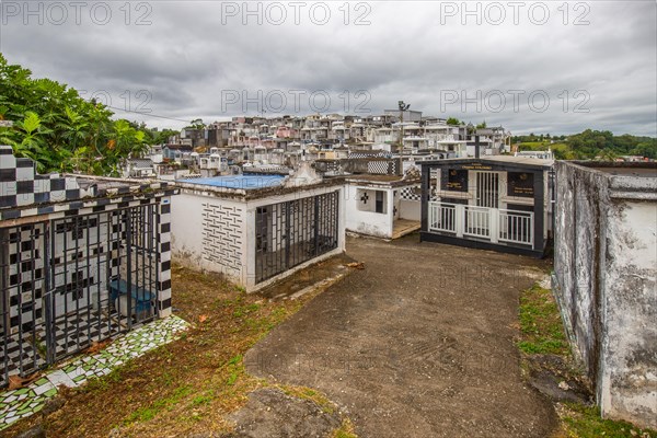 Famous cemetery, many mausoleums or large tombs decorated with tiles, often in black and white. Densely built buildings under a dramatic cloud cover Cimetiere de Morne-a-l'eau, Grand Terre, Guadeloupe, Caribbean, North America