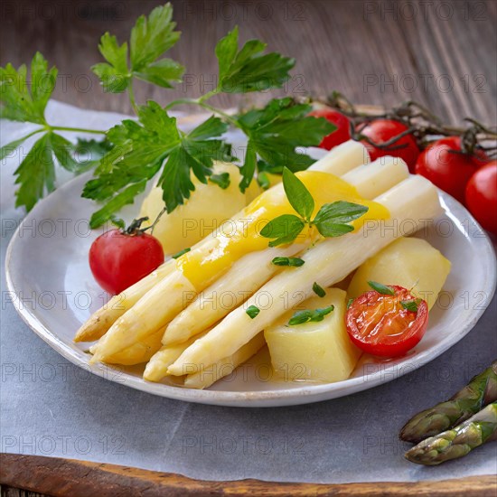 A plate of fresh asparagus and potatoes, garnished with cherry tomatoes and parsley on a wooden table, hollandaise sauce, green asparagus, asparagus spears, AI generated