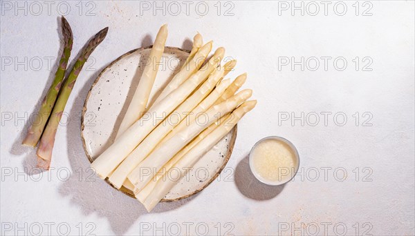 White and green asparagus on a plate with parmesan next to it, presented on wood, AI generated, AI generated