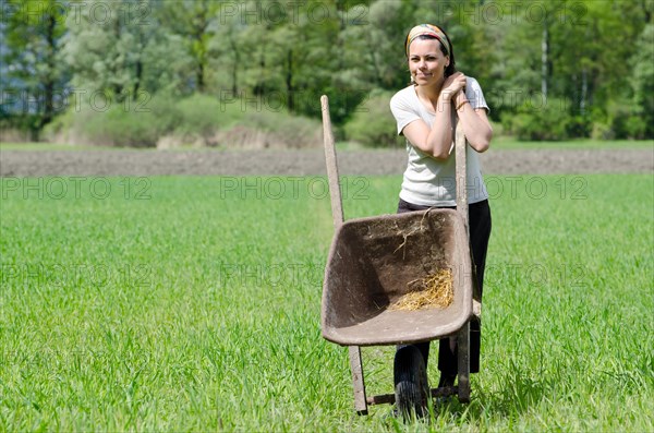 Woman with a Wheelbarrow on the Green Field with Grass. | MR:yes Maria-CH-20-04-2022