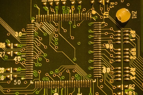 Close-up of microchip, silver solder points and lines on golden lighted electronic computer circuit board, Studio Composition, Quebec, Canada, North America