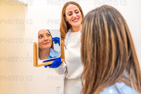 Doctor using mirror to explain to a woman the facial improvements she will perform using hyaluronic acid