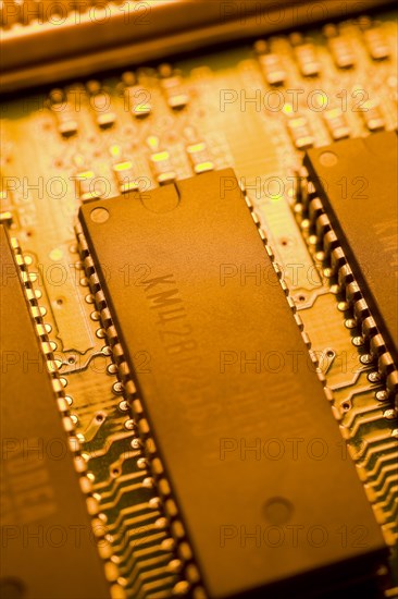 Close-up of orange yellow lighted electronic computer circuit board with memory chips and silver solder points, Studio Composition, Quebec, Canada, North America