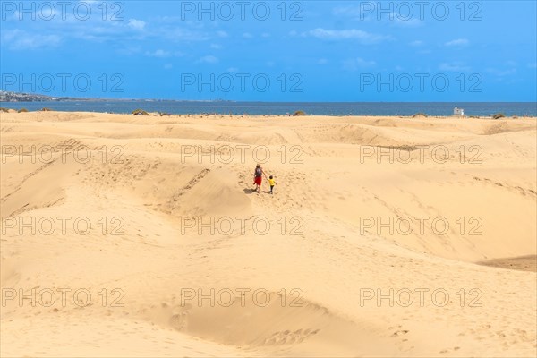 Mother and child walking on summer holidays in the dunes of Maspalomas, Gran Canaria, Canary Islands