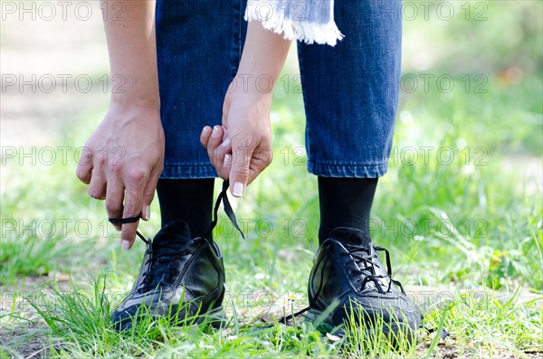 Woman Tying Shoelaces on a Path with Grass