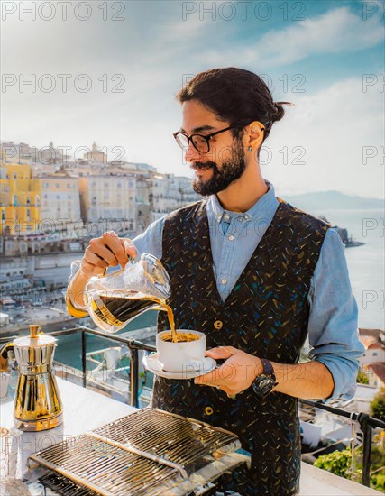 Man brews coffee outdoors using a pourover method with a breathtaking sea view and clear blue sky, Vertical aspect ratio, AI generated
