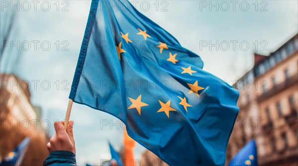Close-up of a man's hand waving the European Union flag in a street protest. Concept of patriotism and pride. AI generated