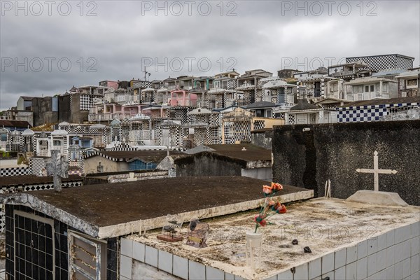 Famous cemetery, many mausoleums or large tombs decorated with tiles, often in black and white. Densely built buildings under a dramatic cloud cover Cimetiere de Morne-a-l'eau, Grand Terre, Guadeloupe, Caribbean, North America