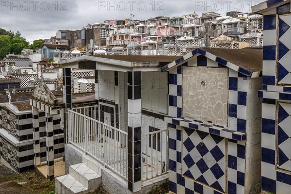 Famous cemetery, many mausoleums or large tombs decorated with tiles, often in black and white. Densely built buildings under a dramatic cloud cover Cimetiere de Morne-a-l'eau, Grand Terre, Guadeloupe, Caribbean, North America