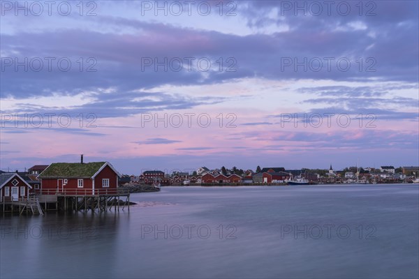 The village of Reine. Typical red wooden houses (rorbuer) on wooden stilts. At night at the time of the midnight sun in good weather, a few clouds in the sky. Early summer. Long exposure. Reine, Moskenesoya, Lofoten, Norway, Europe