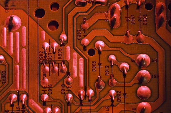 Close-up of red lighted electronic computer circuit board with silver solder points, numbers and lines, Studio Composition, Quebec, Canada, North America
