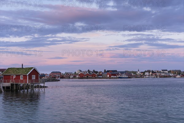 The village of Reine. Typical red wooden houses (rorbuer) on wooden stilts. At night at the time of the midnight sun in good weather, a few clouds in the sky. Early summer. Reine, Moskenesoya, Lofoten, Norway, Europe