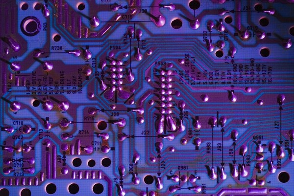 Close-up of purple and blue lighted electronic computer circuit board with silver solder points and lines, Studio Composition, Quebec, Canada, North America