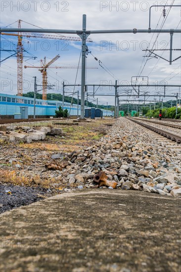 Railway tracks with overhead electric lines and construction in the background, in South Korea