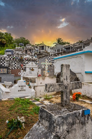 Famous cemetery, many mausoleums or large tombs decorated with tiles, often in black and white. Densely built buildings under a sunset Cimetiere de Morne-a-l'eau, Grand Terre, Guadeloupe, Caribbean, North America