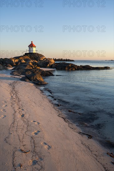 Seascape on the Lofoten Islands. The small lighthouse on the sandy beach of Eggum, sea and rocks. At night at the time of the midnight sun in good weather, blue sky. Golden hour. Early summer. Eggum, Vestvagoya, Lofoten, Norway, Europe