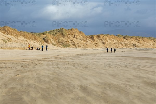 Sand blowing over beach, people, clouds, LLanddwyn Bay, Newborough, Isle of Anglesey, Wales, Great Britain