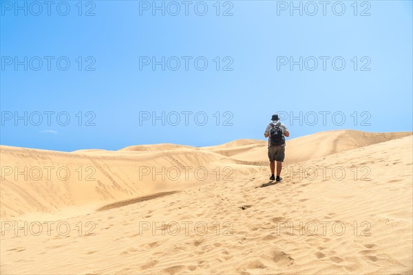 A tourist walking through the dunes of Maspalomas, Gran Canaria, Canary Islands