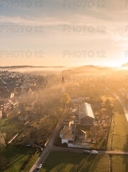 A town awakes in the light of sunrise, shrouded in light fog, Gechingen, Black Forest, Germany, Europe
