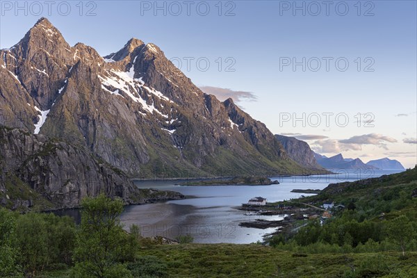 Mountain landscape on the Lofoten Islands. View over the Maervollspollen fjord to mountains in the night sunlight. At night at the time of the midnight sun in good weather, blue sky. Vestvagoya, Lofoten, Norway, Europe