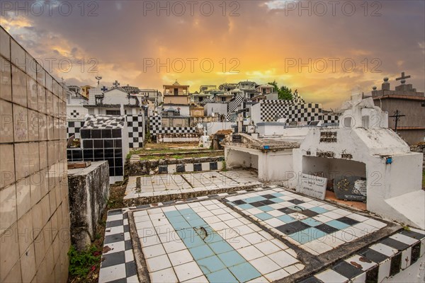 Famous cemetery, many mausoleums or large tombs decorated with tiles, often in black and white. Densely built buildings under a sunset Cimetiere de Morne-a-l'eau, Grand Terre, Guadeloupe, Caribbean, North America