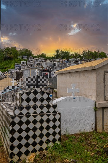 Famous cemetery, many mausoleums or large tombs decorated with tiles, often in black and white. Densely built buildings under a sunset Cimetiere de Morne-a-l'eau, Grand Terre, Guadeloupe, Caribbean, North America