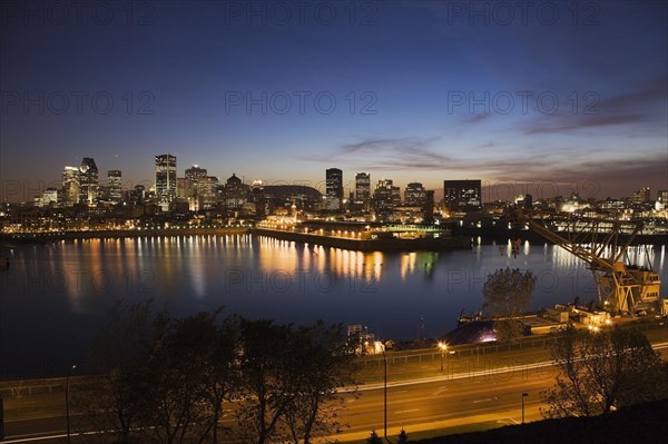 View of Pierre-Dupuy Avenue and Port of Montreal with city skyline showing old and modern architectural buildings illuminated at dusk, Montreal, Quebec, Canada, North America