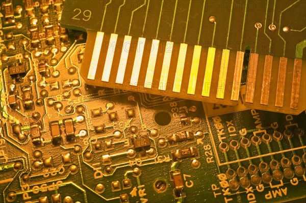 Close-up of golden yellow lighted green electronic computer circuit boards with silver solder points and lines, Studio Composition, Quebec, Canada, North America