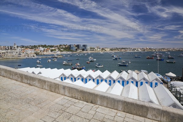 White and blue storage sheds and moored fishing boats in the harbour at Cascais, Portugal, Europe