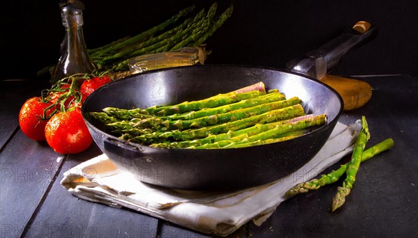 Dark, atmospheric shot of asparagus in a pan next to fresh tomatoes, green asparagus, asparagus spears, AI generated, AI generated
