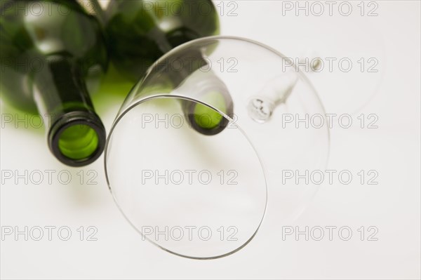 Close-up of two consumed and empty green glass bottles of red wine with tilted wine glass on white background, Studio Composition, Quebec, Canada, North America