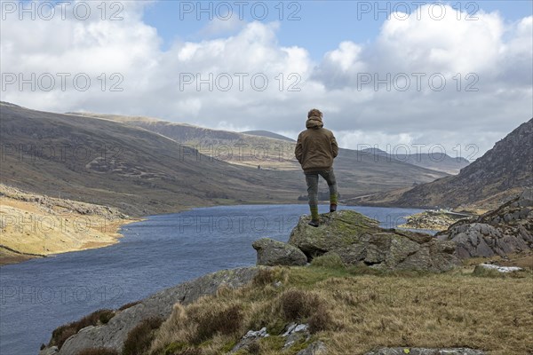 Woman standing on stone, Lake Llyn Ogwen, Snowdonia National Park near Pont Pen-y-benglog, Bethesda, Bangor, Wales, Great Britain