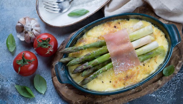 Fine asparagus gratin garnished with fresh cherry tomatoes and garlic on a wooden base, asparagus gratin with green asparagus, cheese and ham, KI generated, AI generated
