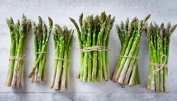 Assorted bundles of green asparagus tied with kitchen string on white background, AI generated, AI generated