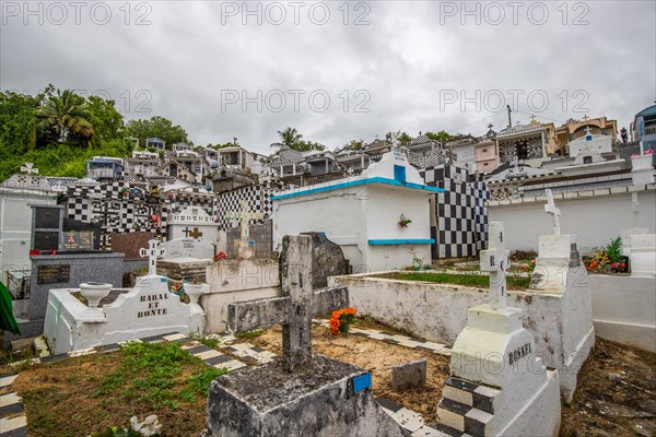 Famous cemetery, many mausoleums or large tombs decorated with tiles, often in black and white. Densely built buildings under a dramatic cloud cover Cimetiere de Morne-a-l'eau, Grand Terre, Guadeloupe, Caribbean, North America