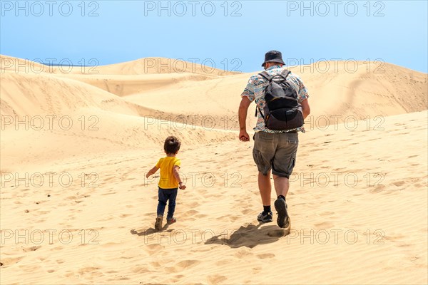 Father and son on vacation laughing running in the dunes of Maspalomas, Gran Canaria, Canary Islands