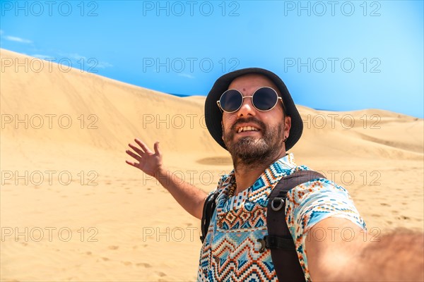Selfie of a tourist with glasses and hat enjoying in the dunes of Maspalomas, Gran Canaria, Canary Islands
