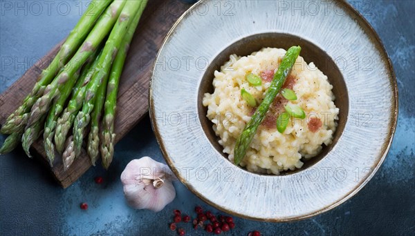 A plate of risotto with asparagus and pieces of bacon next to garlic cloves, risotto with green asparagus, KI generated, AI generated