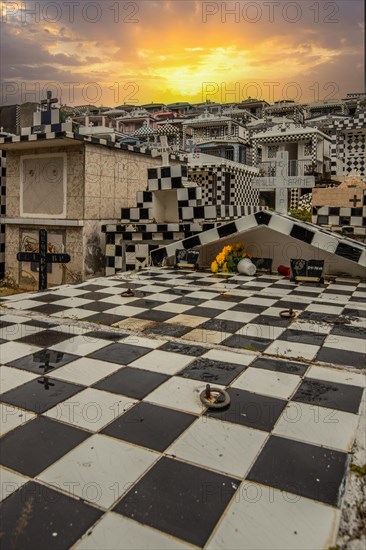 Famous cemetery, many mausoleums or large tombs decorated with tiles, often in black and white. Densely built buildings under a sunset Cimetiere de Morne-a-l'eau, Grand Terre, Guadeloupe, Caribbean, North America