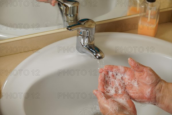 A woman washes her hands under the faucet. A stream of drinking water flows into the bathroom sink. Hand washing and hygiene. Water consumption, environment, pollution and the concept of scarcity