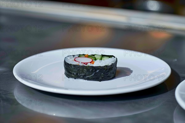 A piece of sushi with rice and cucumber wrapped in seaweed on a plain white plate, AI generated