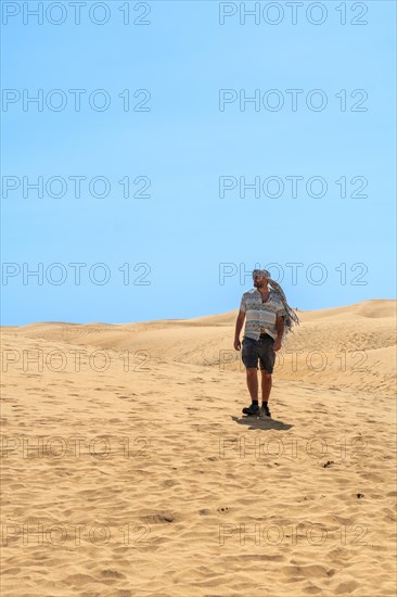 Tourist man with turban in summer walking in the dunes of Maspalomas, Gran Canaria, Canary Islands