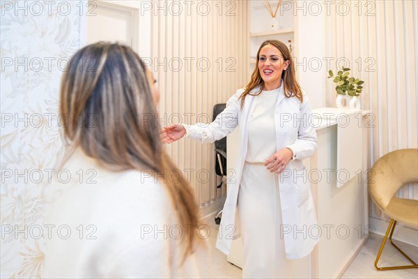 Female aesthetic doctor with lab coat and elegant clothes welcomes a patient at the entrance of a beauty clinic