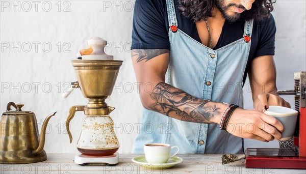 Bearded hipster man with tattoos using a manual coffee grinder next to a vintage kettle, horizontal, AI generated