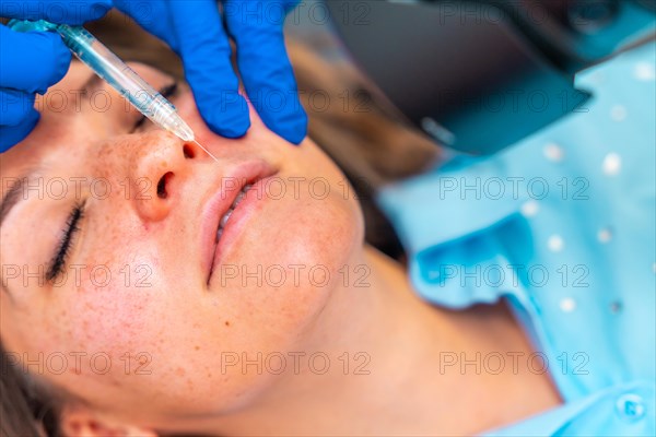 Close-up top view of a woman receiving a botox injection to the lips lying on stretcher in the clinic