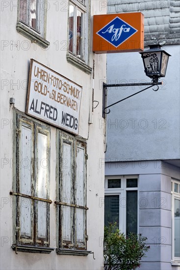Cantilever sign, AGFA Film und Foto advertising sign, abandoned photo shop with watch shop, jewellery, gold and silver, closed shutters, street lamp, dilapidated house, old town, Ortenberg, Vogelsberg, Wetterau, Hesse, Germany, Europe
