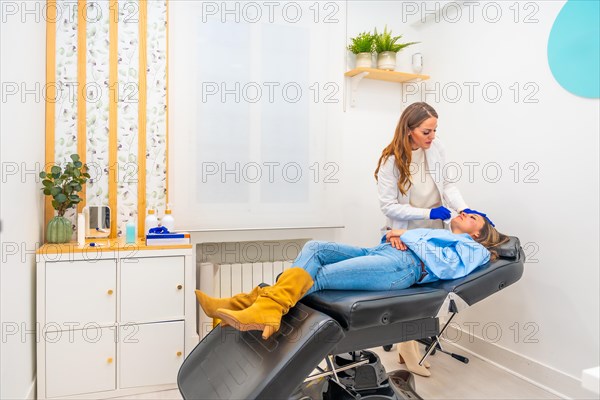 Cosmetologist working in a innovative beautician clinic injecting hyaluronic acid to the face of a woman