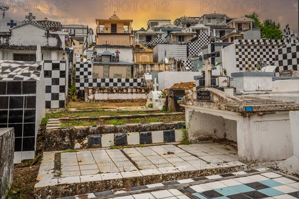 Famous cemetery, many mausoleums or large tombs decorated with tiles, often in black and white. Densely built buildings under a sunset Cimetiere de Morne-a-l'eau, Grand Terre, Guadeloupe, Caribbean, North America