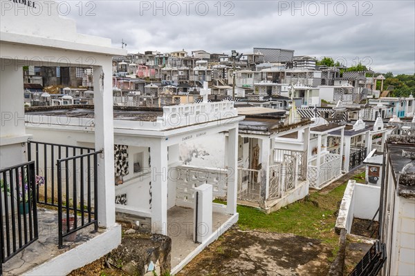 Famous cemetery, many mausoleums or large tombs decorated with tiles, often in black and white. Densely built buildings under a dramatic cloud cover Cimetiere de Morne-a-l'eau, Grand Terre, Guadeloupe, Caribbean, North America