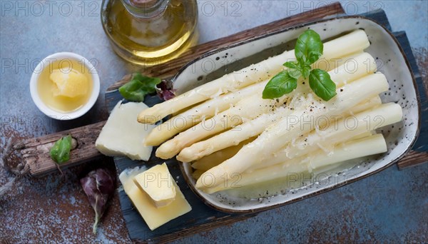Fresh white asparagus garnished with cheese on a rustic wooden board, next to olive oil, cooked white asparagus sprinkled with parmesan, KI generated, AI generated